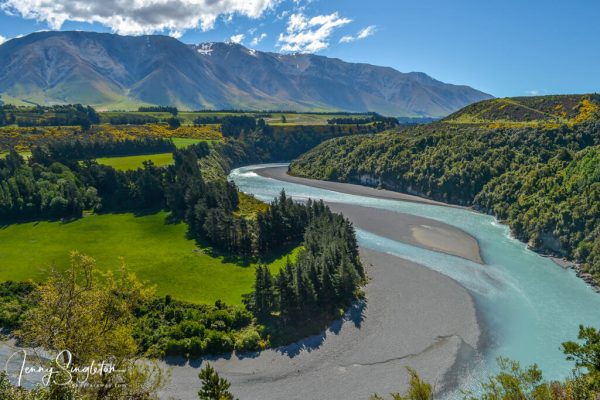 Rakaia Gorge Walkway, Canterbury, New Zealand The Rakaia River surrounded by vegetation, with farmland and mountains behind, seen from the Rakaia Gorge Walkway.